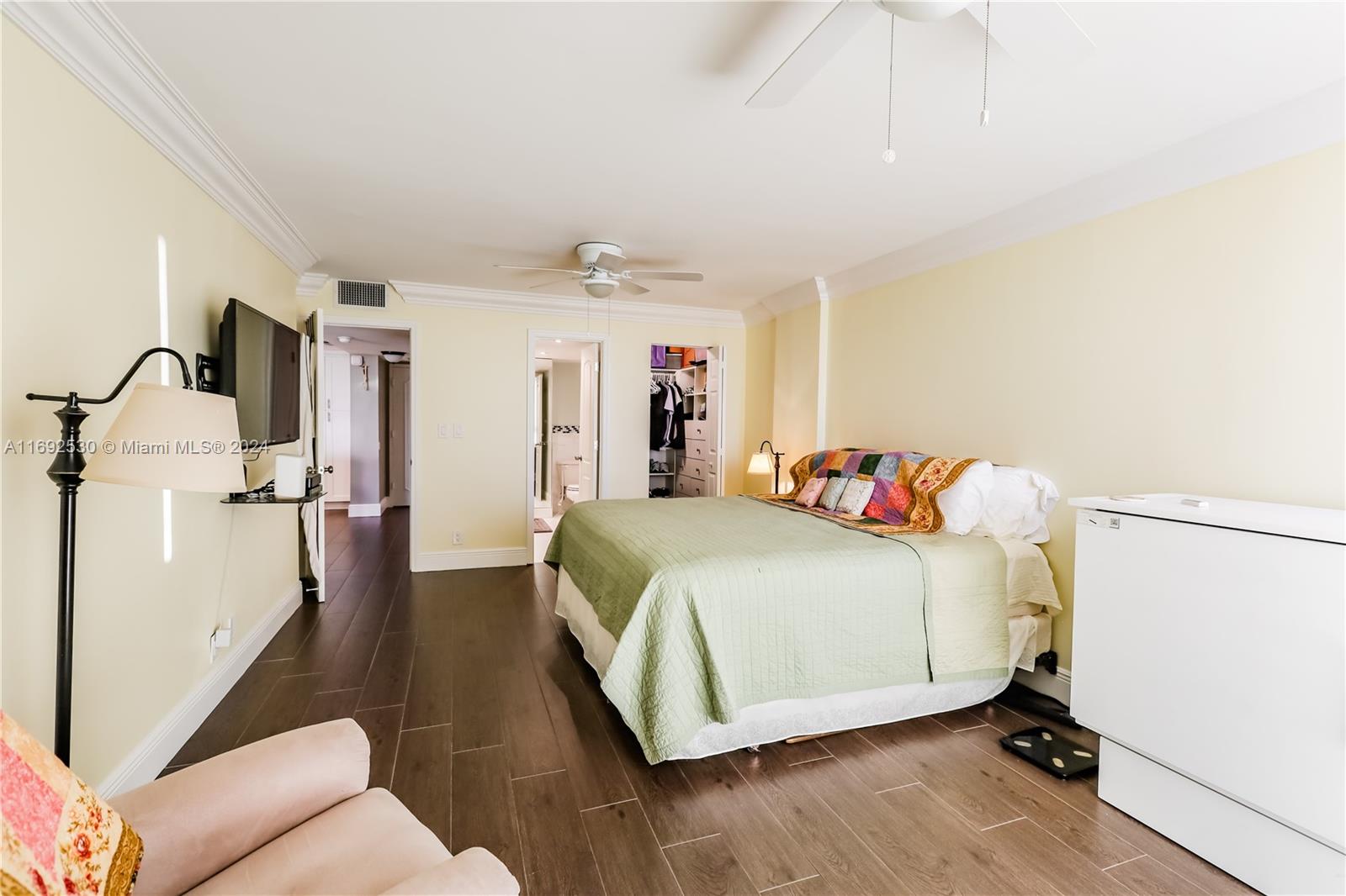 bedroom with a walk in closet, ceiling fan, dark hardwood / wood-style floors, white fridge, and a closet