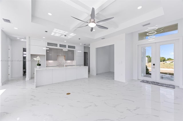 interior space featuring a raised ceiling, ceiling fan, french doors, and sink