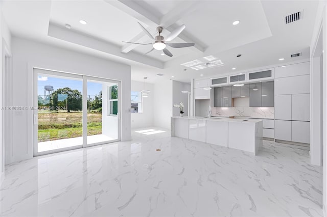 unfurnished living room with a tray ceiling, ceiling fan, and sink