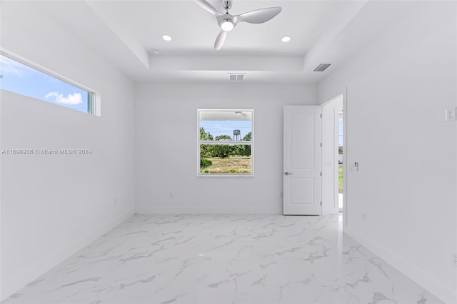 empty room with a raised ceiling and ceiling fan