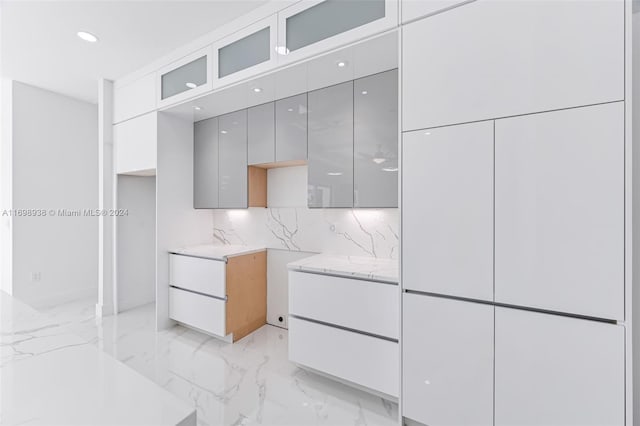 kitchen featuring gray cabinetry, decorative backsplash, and light stone counters