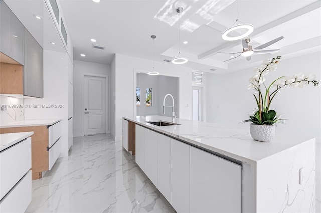 kitchen with light stone counters, ceiling fan, sink, decorative light fixtures, and gray cabinets