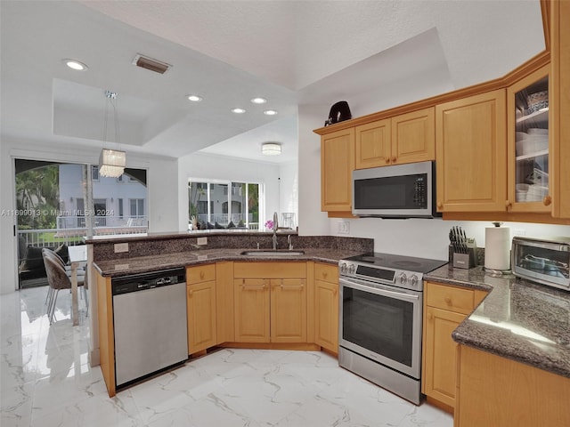 kitchen with kitchen peninsula, appliances with stainless steel finishes, sink, decorative light fixtures, and a chandelier