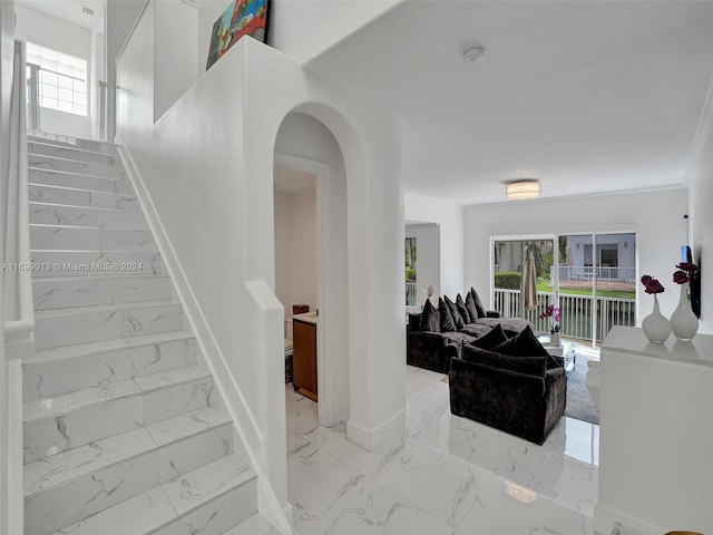 stairway with plenty of natural light and ornamental molding