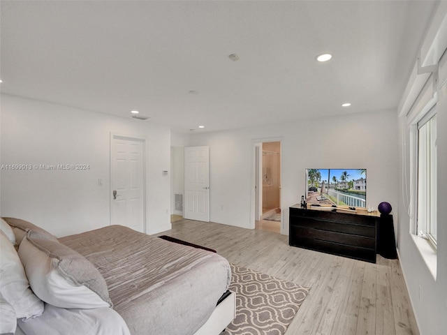 bedroom with ensuite bathroom and light hardwood / wood-style floors