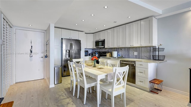 kitchen with white cabinets, decorative backsplash, light wood-type flooring, and appliances with stainless steel finishes