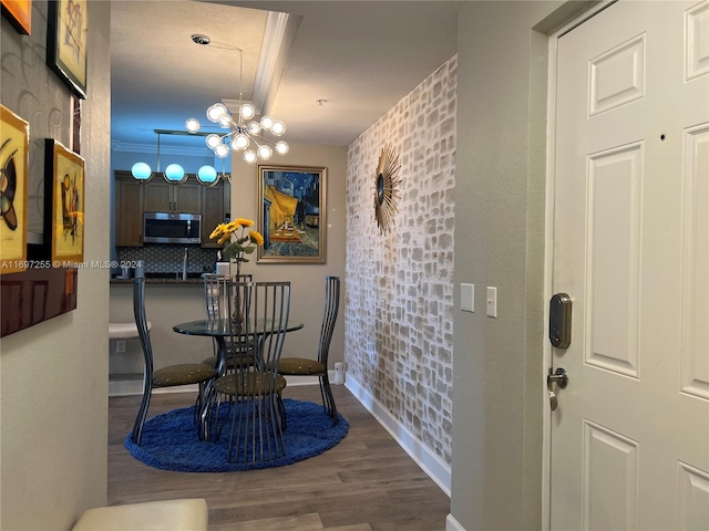 dining area with dark wood-type flooring, a notable chandelier, and ornamental molding