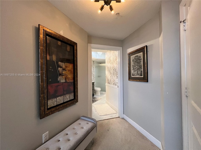 hallway with light colored carpet and a textured ceiling