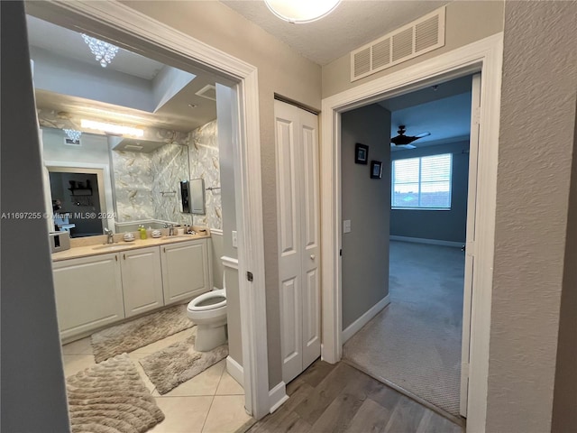 bathroom with hardwood / wood-style floors, vanity, ceiling fan, and toilet