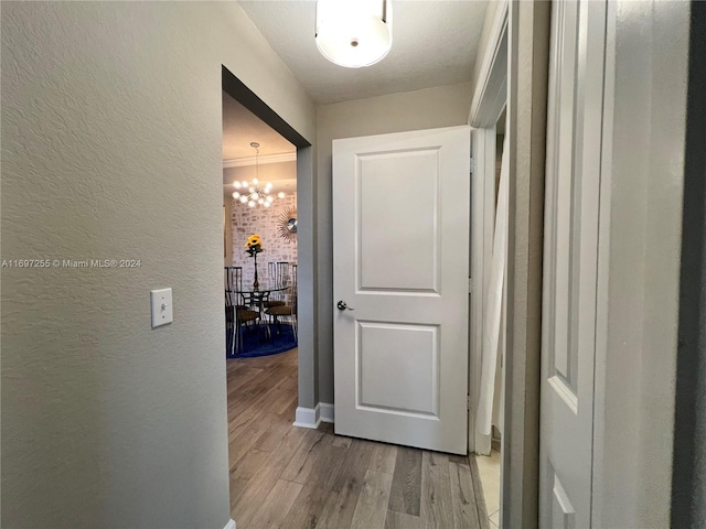 hallway with light wood-type flooring and a notable chandelier