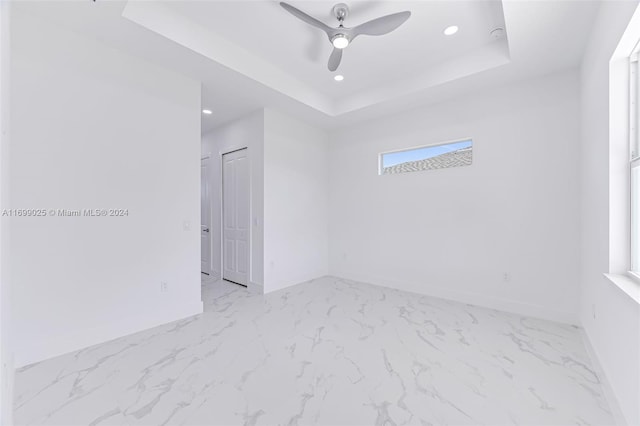 empty room featuring a tray ceiling and ceiling fan