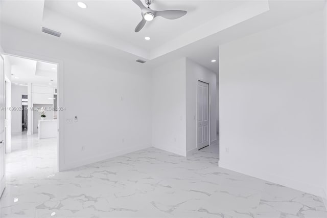 unfurnished room featuring a raised ceiling and ceiling fan