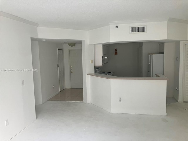 kitchen with kitchen peninsula, white fridge, and a textured ceiling