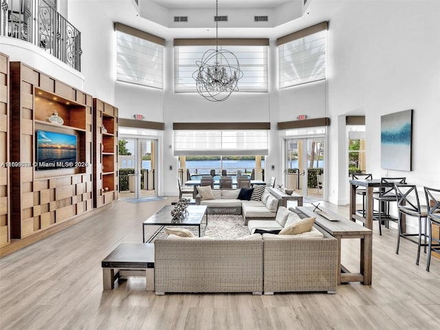 living room with plenty of natural light, light hardwood / wood-style flooring, a chandelier, and french doors