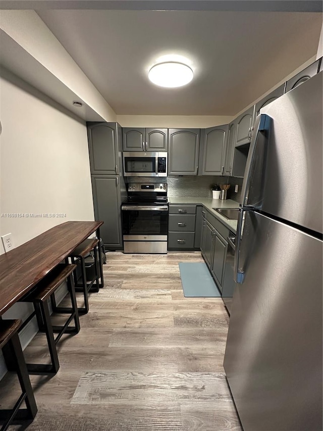 kitchen with gray cabinets, sink, light hardwood / wood-style floors, and appliances with stainless steel finishes