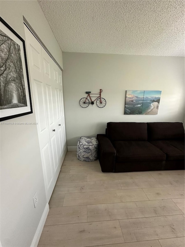 living room featuring light wood-type flooring and a textured ceiling