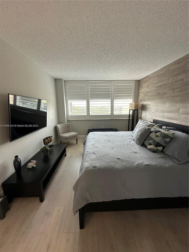 bedroom with a textured ceiling and light hardwood / wood-style flooring