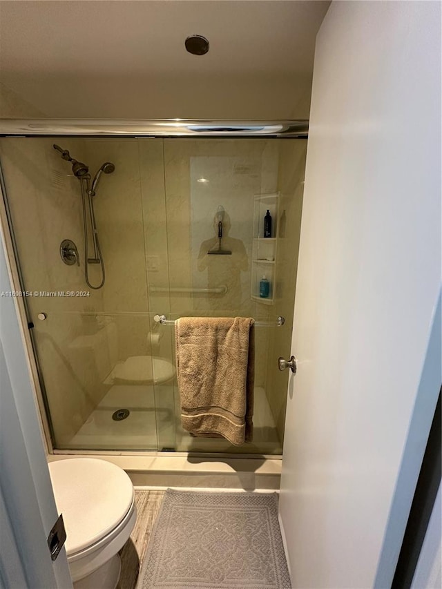 bathroom with toilet and a shower with door