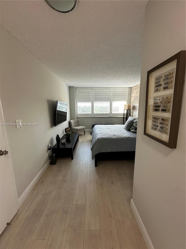 bedroom featuring a textured ceiling and light hardwood / wood-style flooring