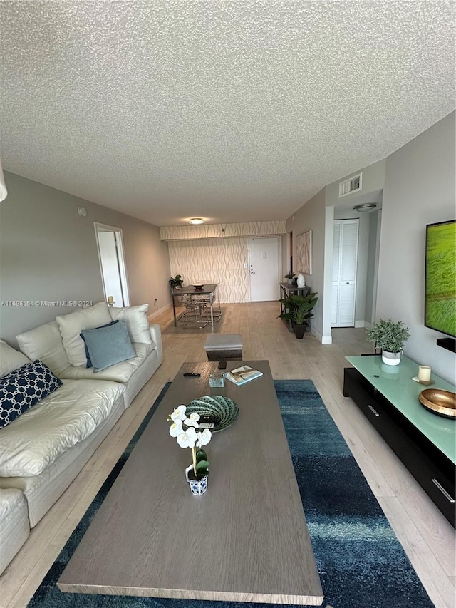 living room featuring a textured ceiling and light hardwood / wood-style flooring