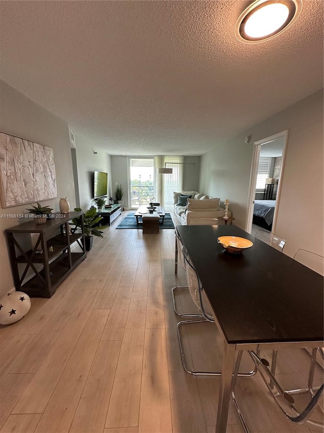 dining space with wood-type flooring and a textured ceiling