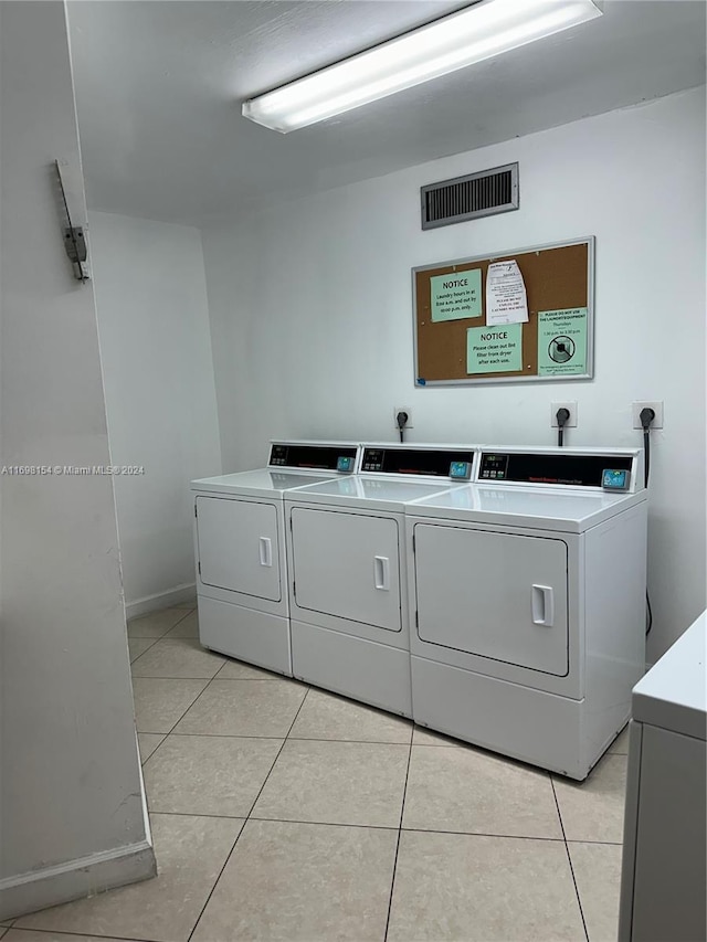 clothes washing area with independent washer and dryer and light tile patterned flooring