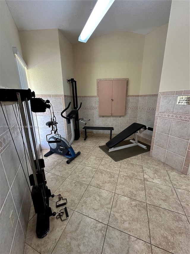 exercise area featuring light tile patterned floors and tile walls