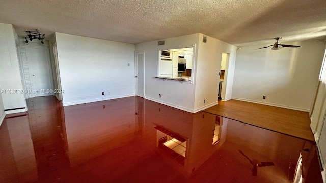 unfurnished living room with ceiling fan, wood-type flooring, and a textured ceiling