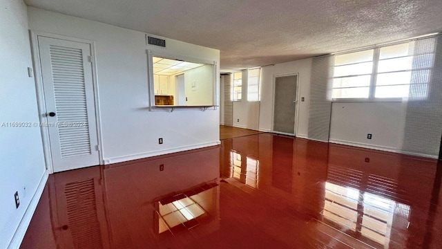 spare room with a textured ceiling, hardwood / wood-style flooring, and plenty of natural light