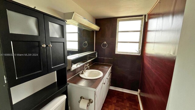 bathroom with parquet flooring, vanity, and toilet