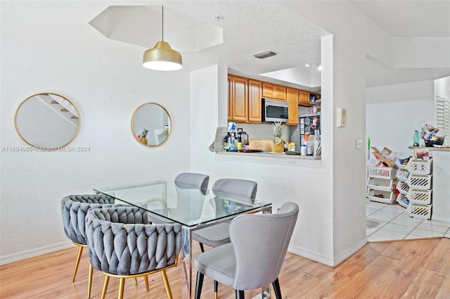 dining space featuring a textured ceiling and light hardwood / wood-style flooring