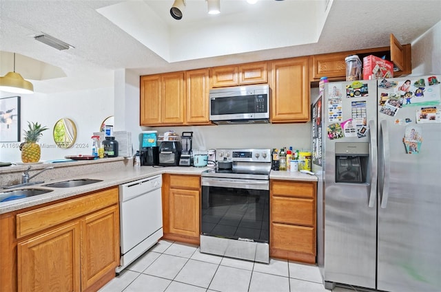 kitchen with sink, a raised ceiling, a textured ceiling, light tile patterned flooring, and appliances with stainless steel finishes