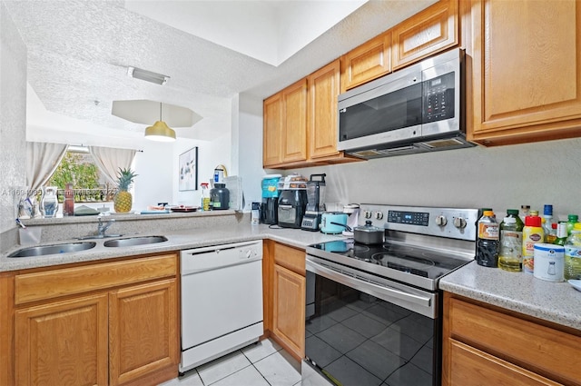 kitchen featuring a textured ceiling, light tile patterned floors, sink, and appliances with stainless steel finishes