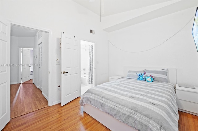 bedroom with connected bathroom and wood-type flooring