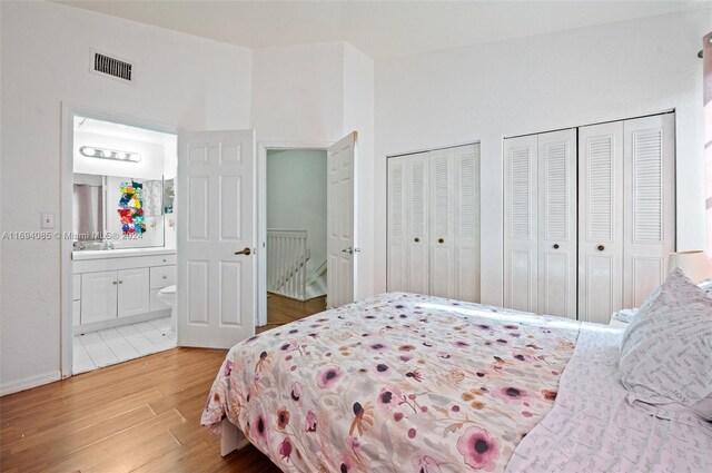 bedroom featuring hardwood / wood-style floors, connected bathroom, and multiple closets