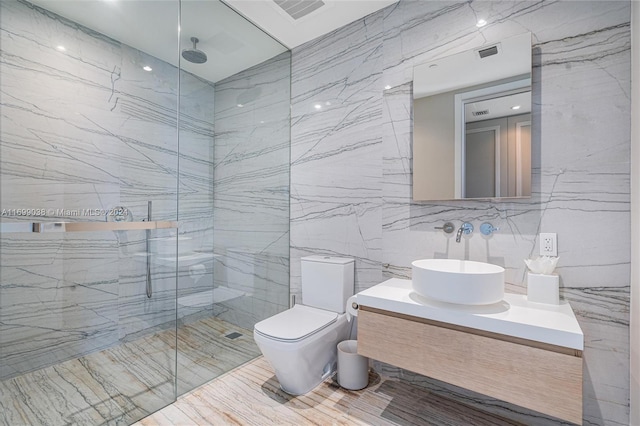 bathroom featuring vanity, toilet, a shower with door, and tile walls