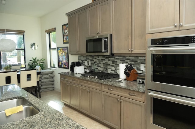 kitchen with backsplash, light stone countertops, light tile patterned floors, and appliances with stainless steel finishes