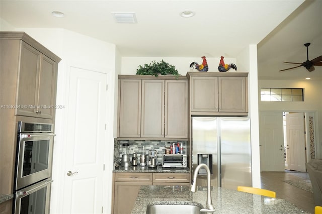 kitchen with stone counters, sink, ceiling fan, decorative backsplash, and appliances with stainless steel finishes