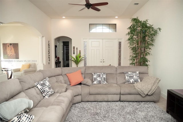 living room featuring carpet floors, ceiling fan, and a towering ceiling