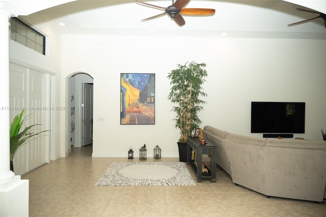 living room featuring ceiling fan, light tile patterned flooring, and a towering ceiling