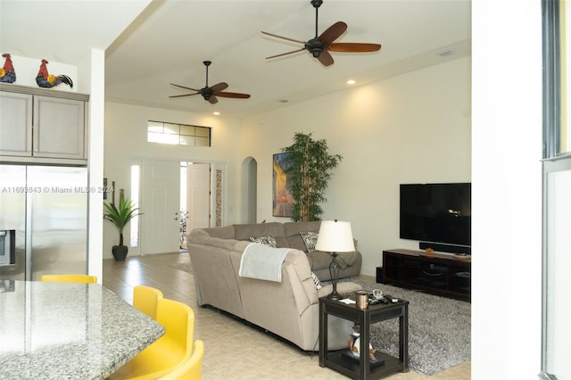 living room with ceiling fan, light tile patterned floors, and a towering ceiling