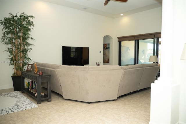 living room with light tile patterned floors, a towering ceiling, and ceiling fan