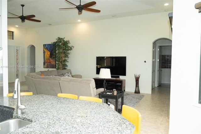 tiled living room with a high ceiling, ceiling fan, and sink