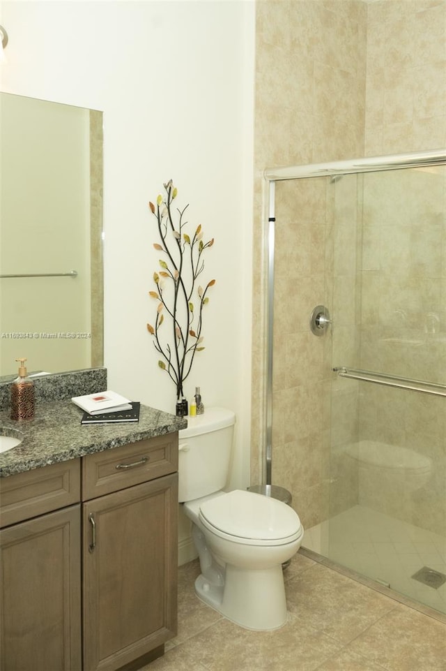 bathroom with tile patterned flooring, vanity, toilet, and an enclosed shower