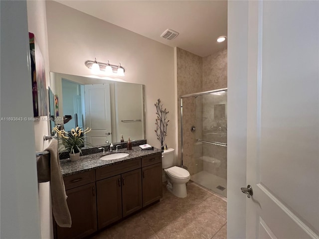 bathroom with tile patterned floors, a shower with door, vanity, and toilet