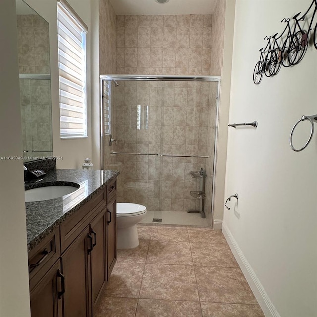 bathroom featuring tile patterned floors, vanity, toilet, and walk in shower