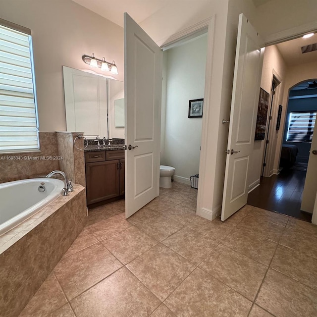 bathroom featuring tiled bath, tile patterned flooring, vanity, and toilet