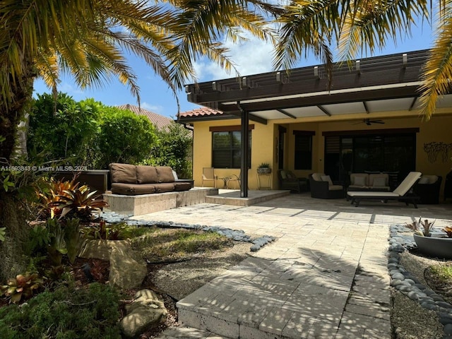 rear view of property with ceiling fan, a patio area, and an outdoor living space