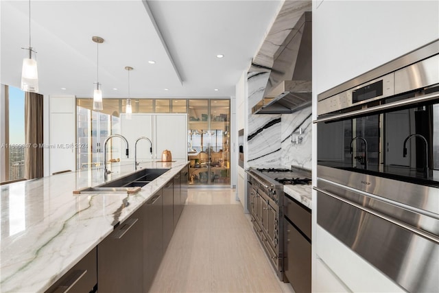 kitchen featuring light stone countertops, sink, hanging light fixtures, backsplash, and appliances with stainless steel finishes