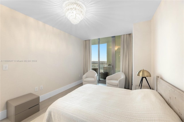 bedroom featuring access to exterior, light hardwood / wood-style flooring, and a chandelier